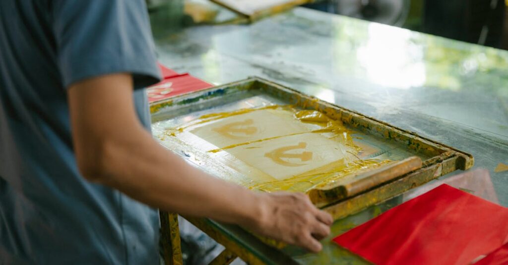 Artisan crafting screen prints indoors, showcasing creativity and skill in handmade art production.